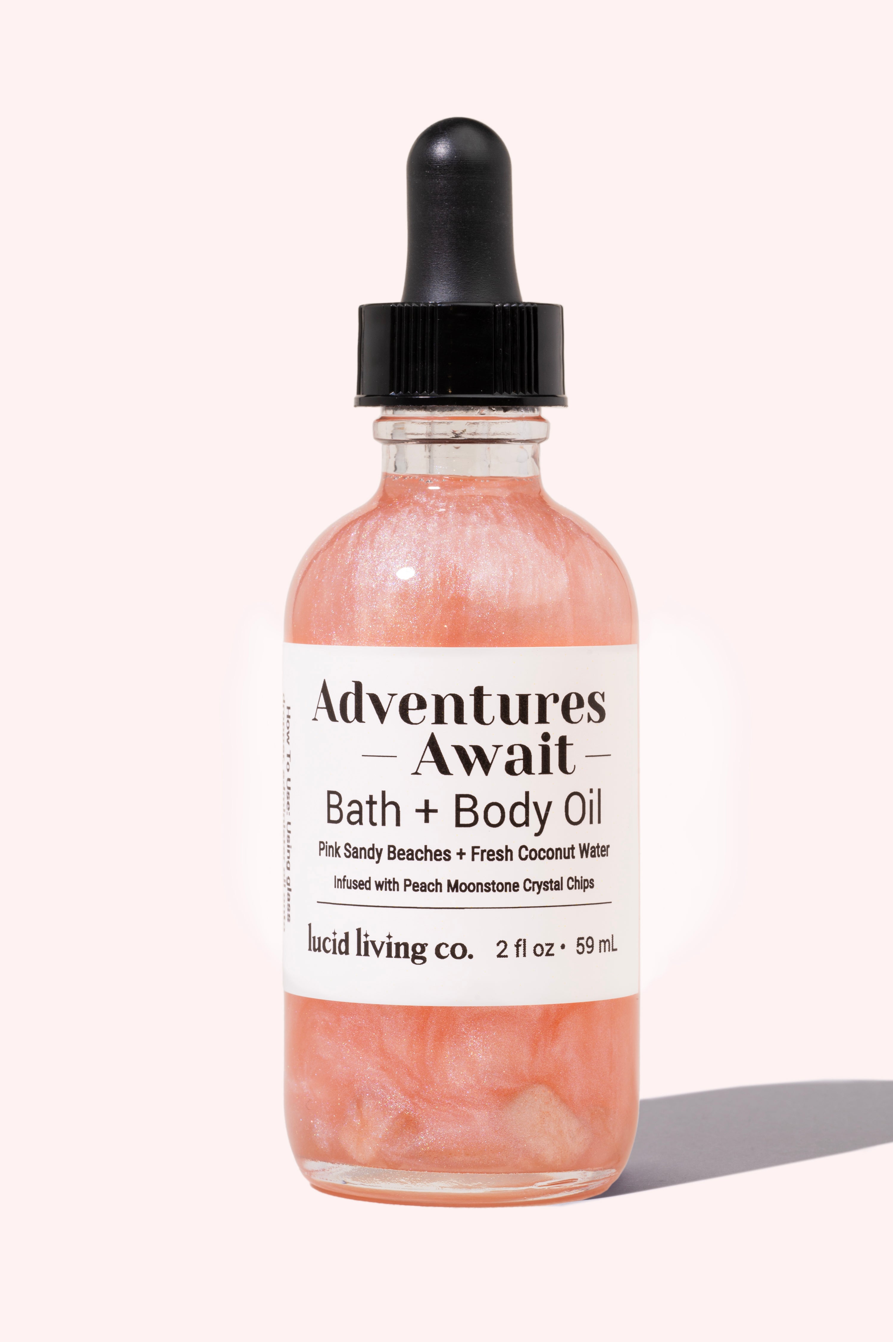 Adventures Await Bath & Body Oil with pink sandy beaches scent, fresh coconut water, and Peach Moonstone chips.