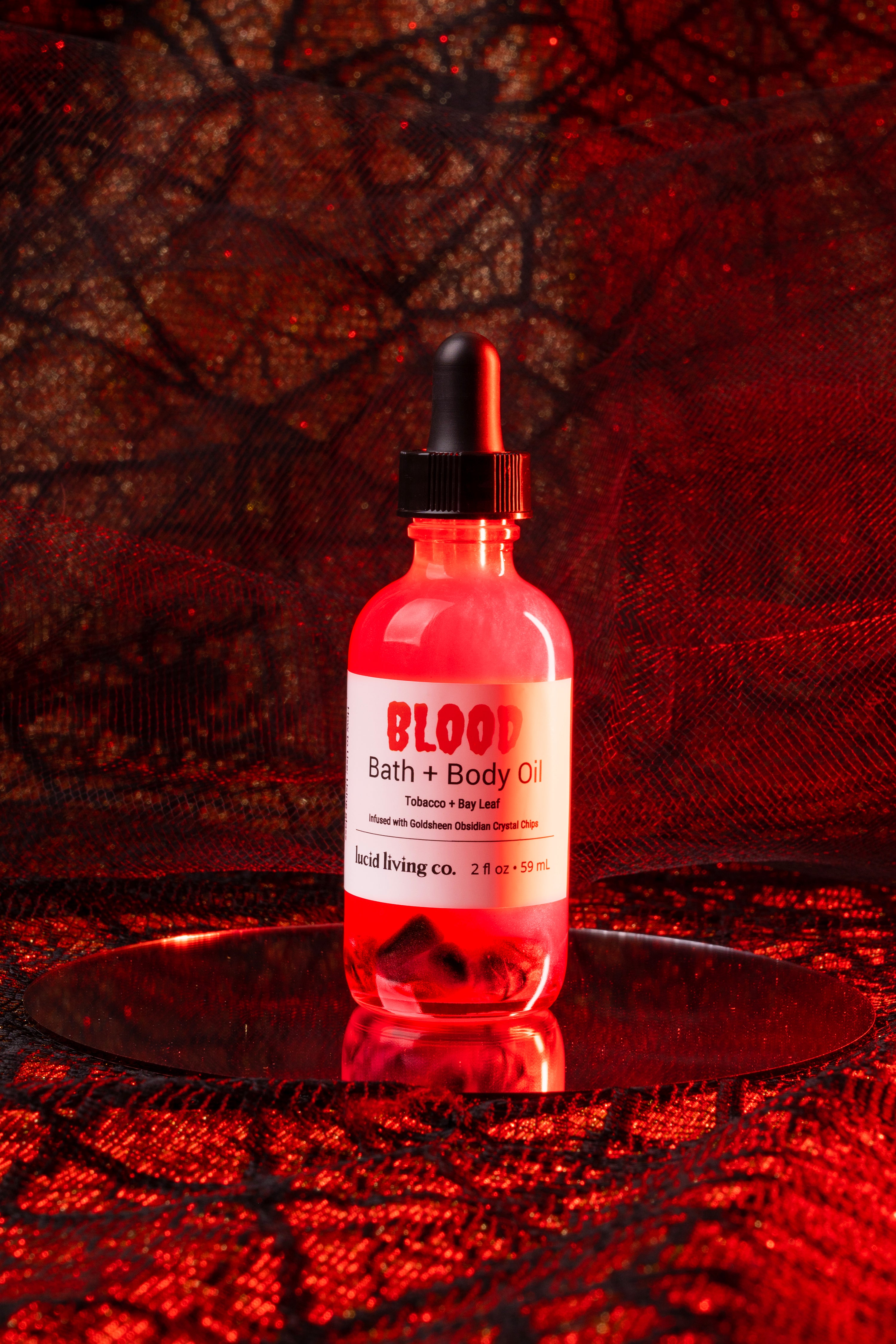 BLOOD Bath & Body Oil bottle with smoky tobacco and bay leaf scent, infused with Goldsheen Obsidian crystal chips.