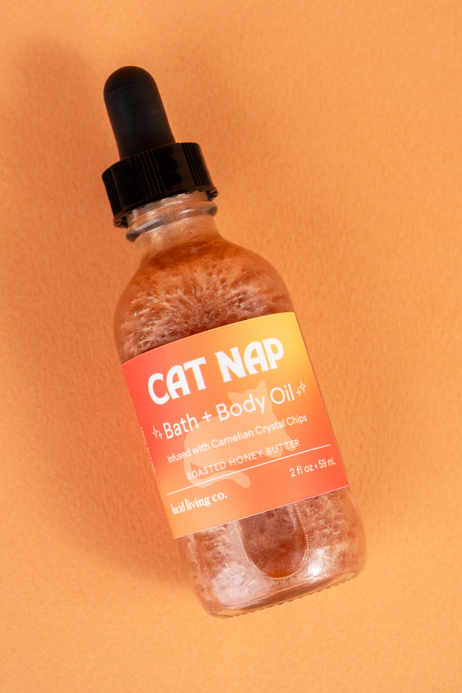 Cat Nap Bath & Body Oil bottle with caramel-toned label and dropper, infused with Carnelian crystal chips.