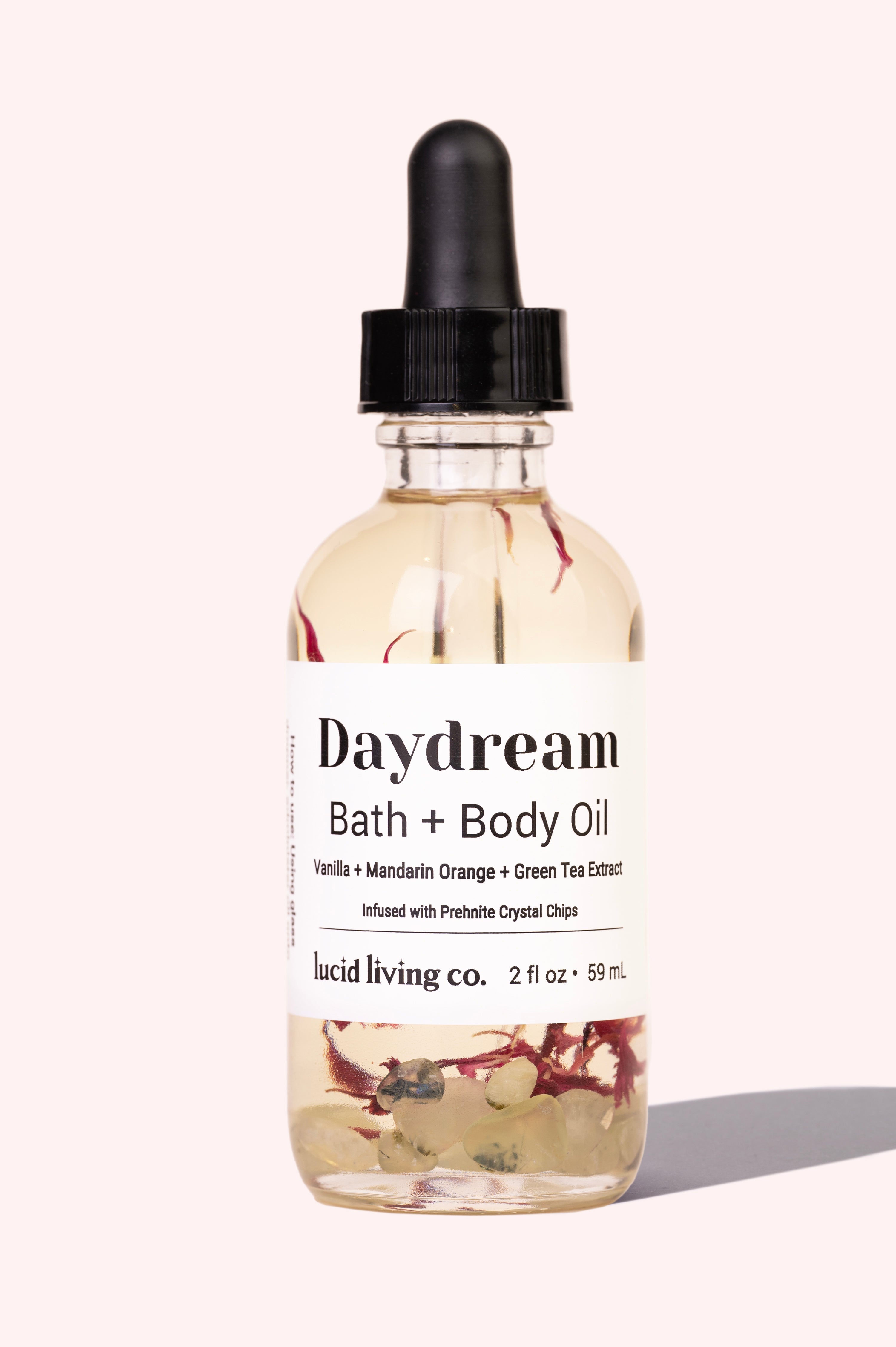 Daydream Bath & Body Oil with vanilla, mandarin orange, green tea, and prehnite crystal chips in clear glass bottle.