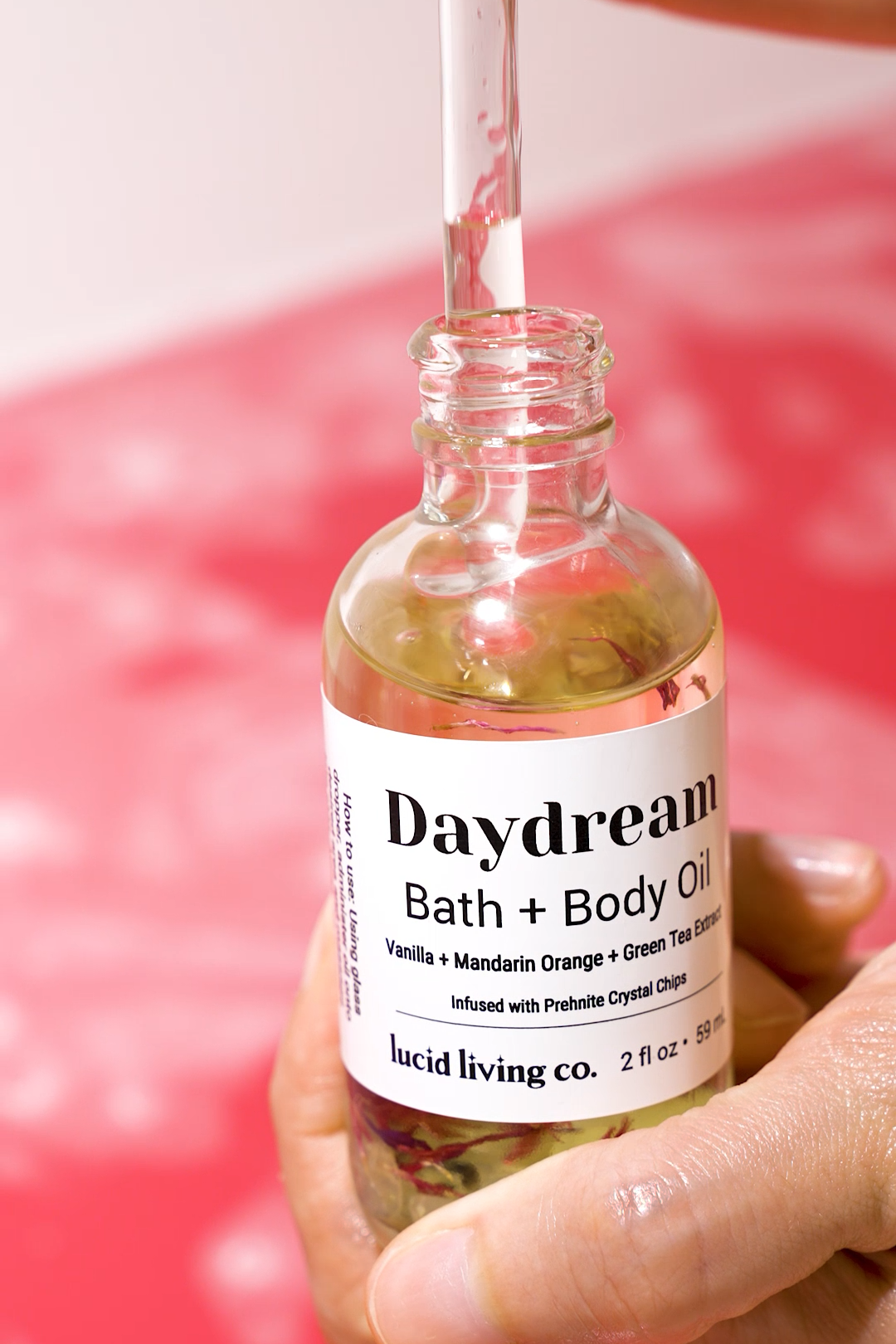 Daydream Bath & Body Oil with vanilla, mandarin orange, green tea, and Prehnite crystal chips in clear glass bottle.