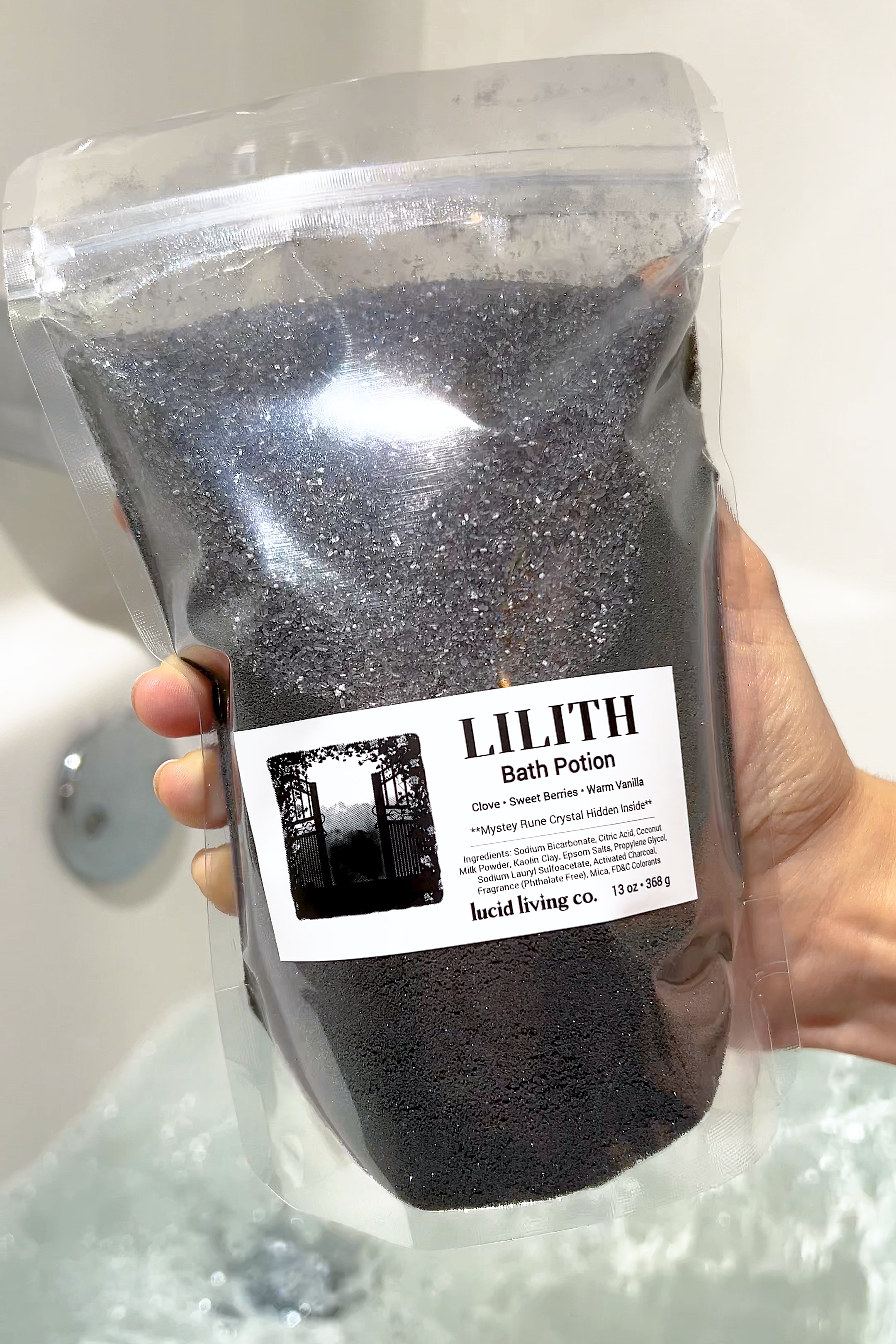 Clear pouch of LILITH "The Dark Mother" Bath Potion with clove, berries, and vanilla scent held over water.