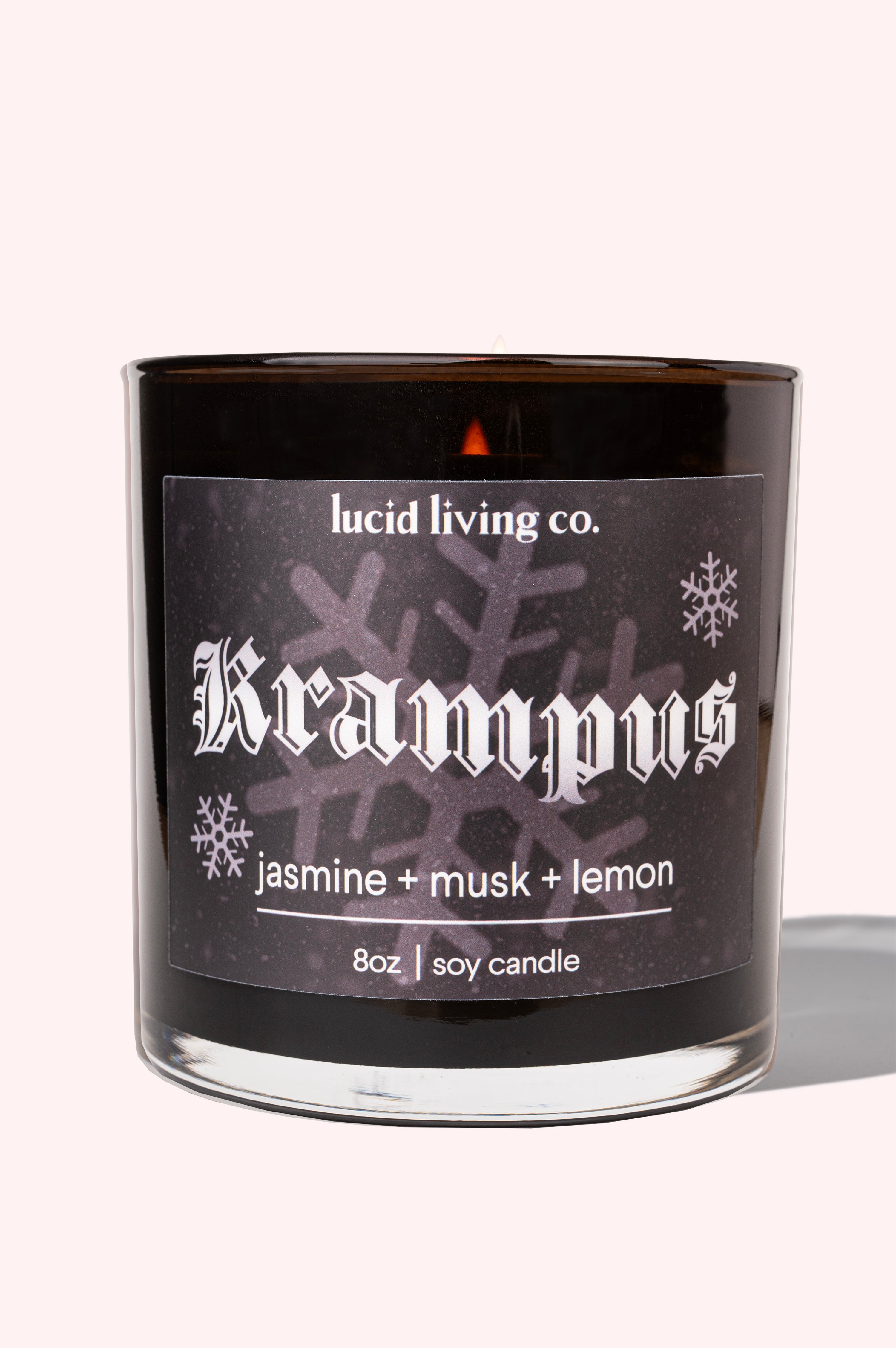 Krampus Soy Candle by Lucid Living Co. with jasmine, musk, and lemon scent in black glass jar with snowflake design.