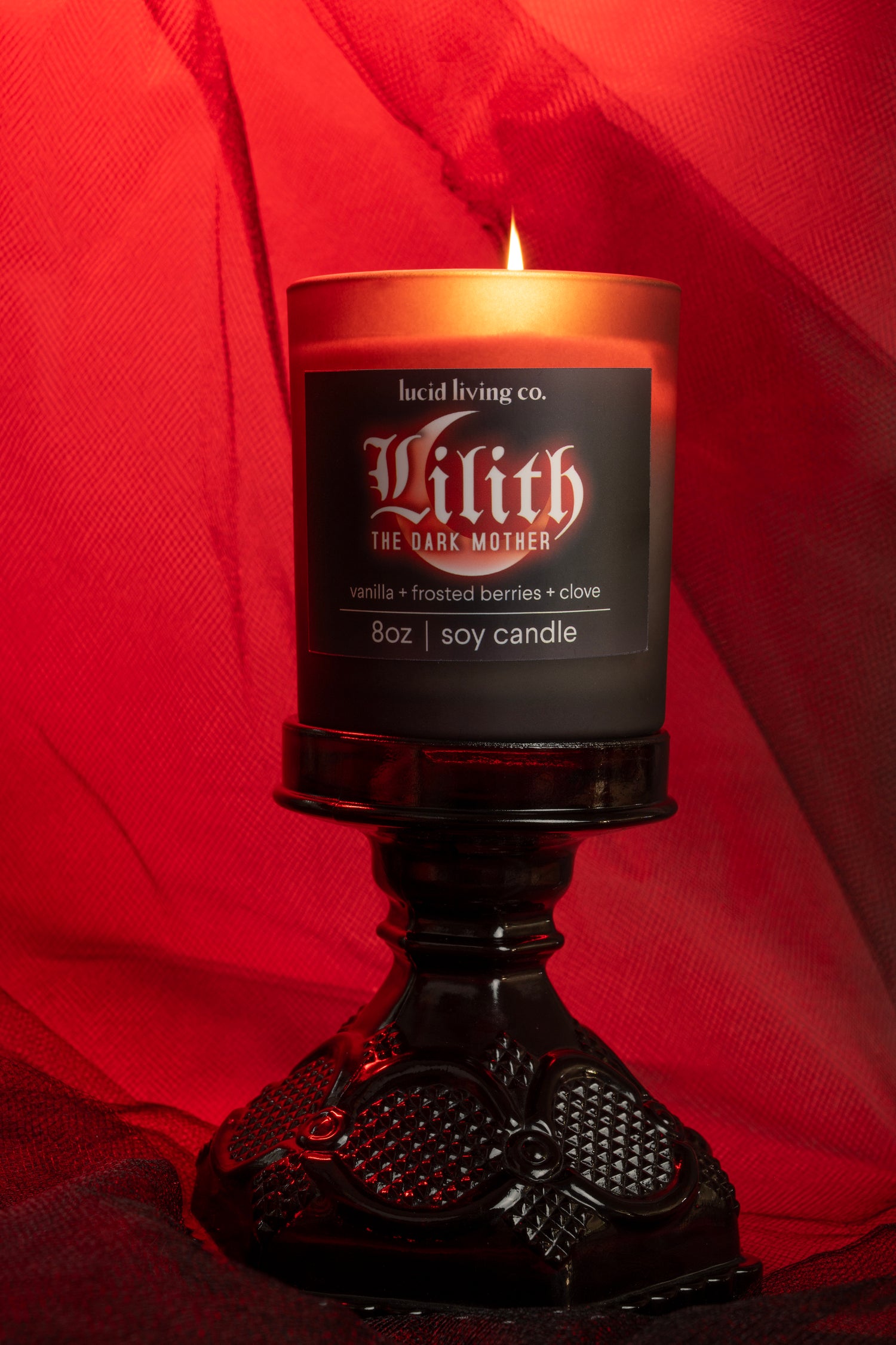 LILITH Bundle soy candle with vanilla, frosted berries, and clove scent glowing on black ornate holder.