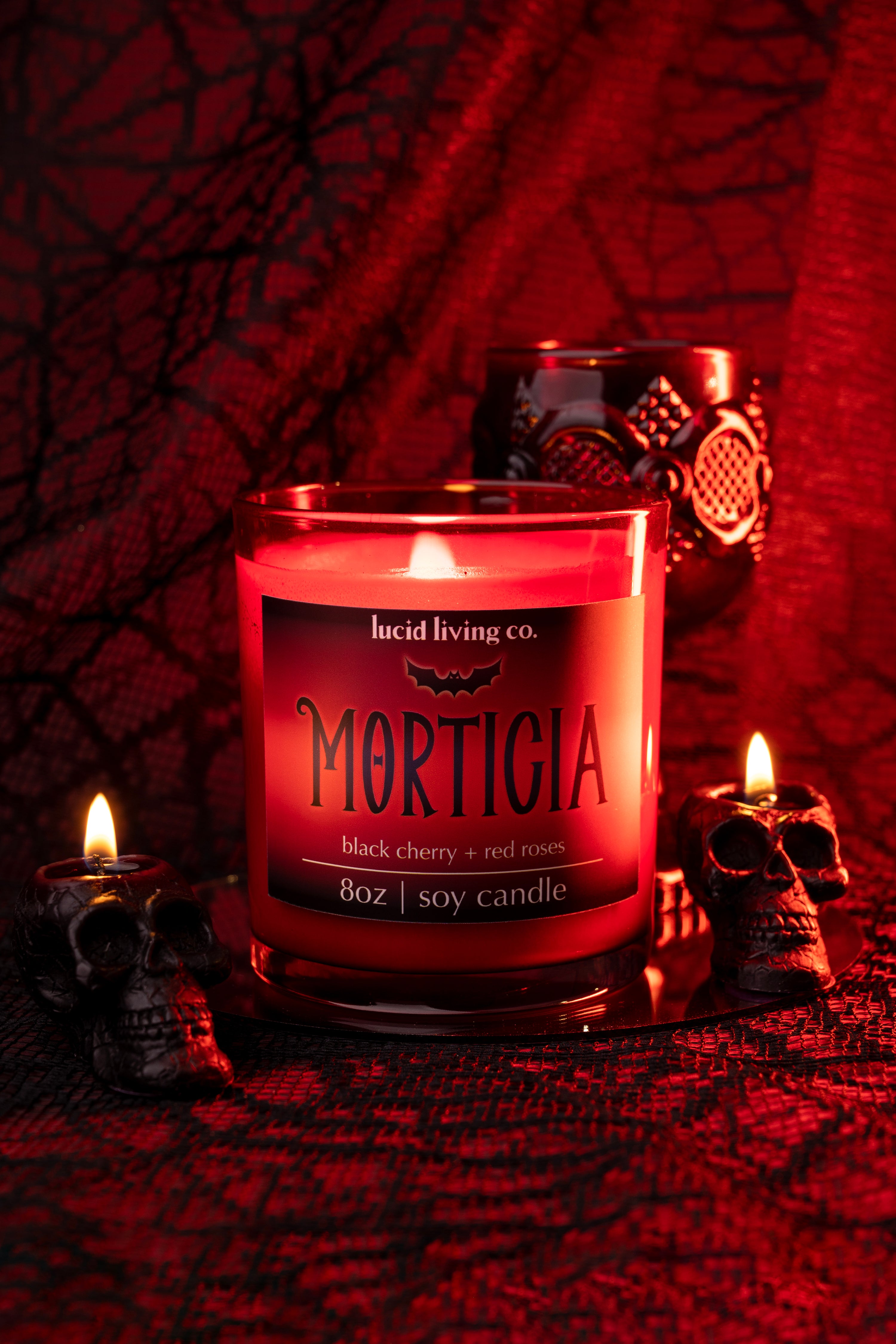 MORTICIA Bundle black cherry red roses soy candle lit with skull candles on dark red fabric background