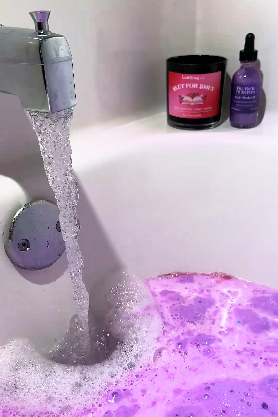 Mystical Fae Bath Potion dissolving in tub water with purple bubbles under running faucet for a soothing soak.
