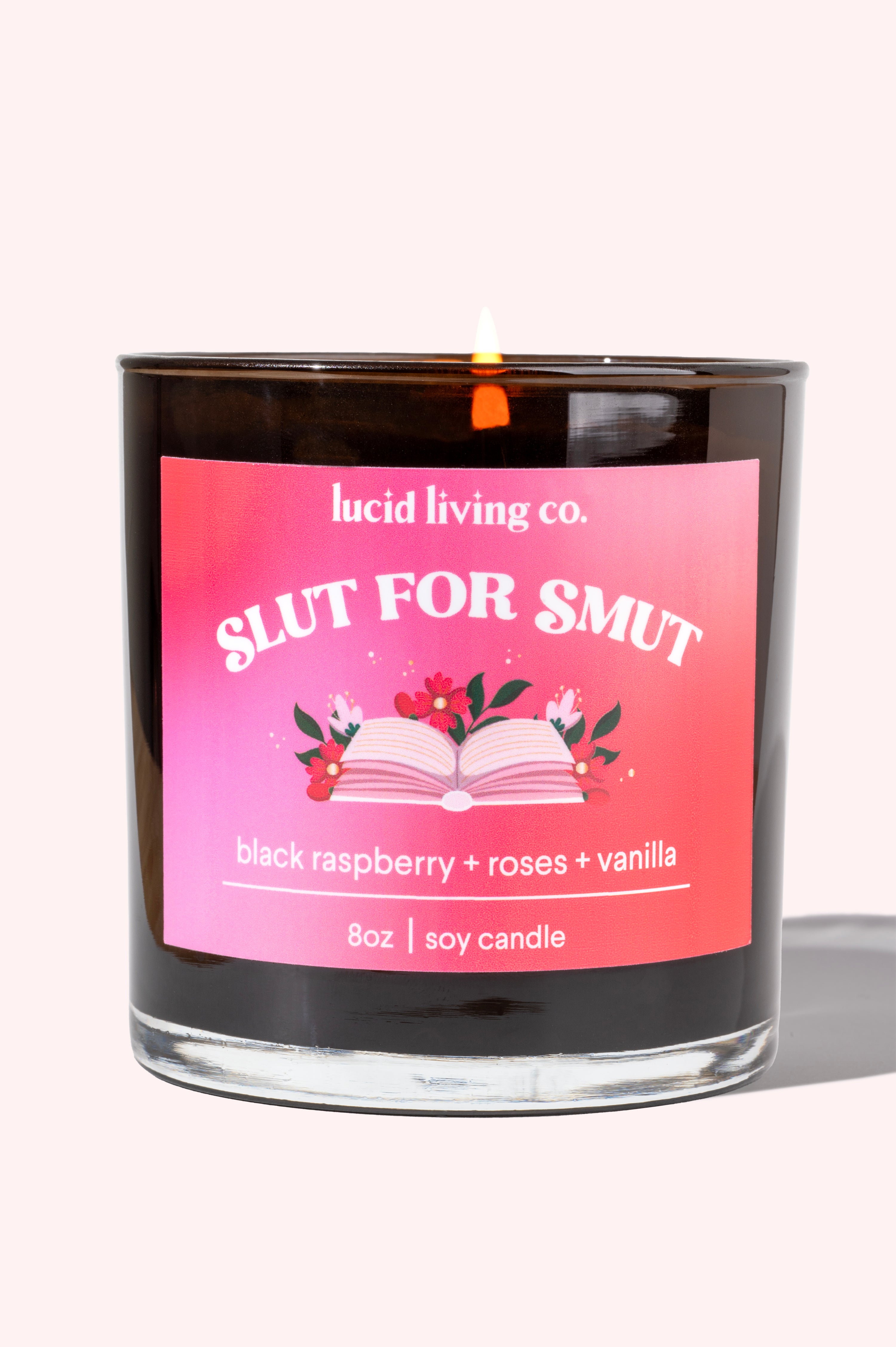 Slut for Smut soy candle with black raspberry, roses, and vanilla scent in a black glass jar lit on a white background