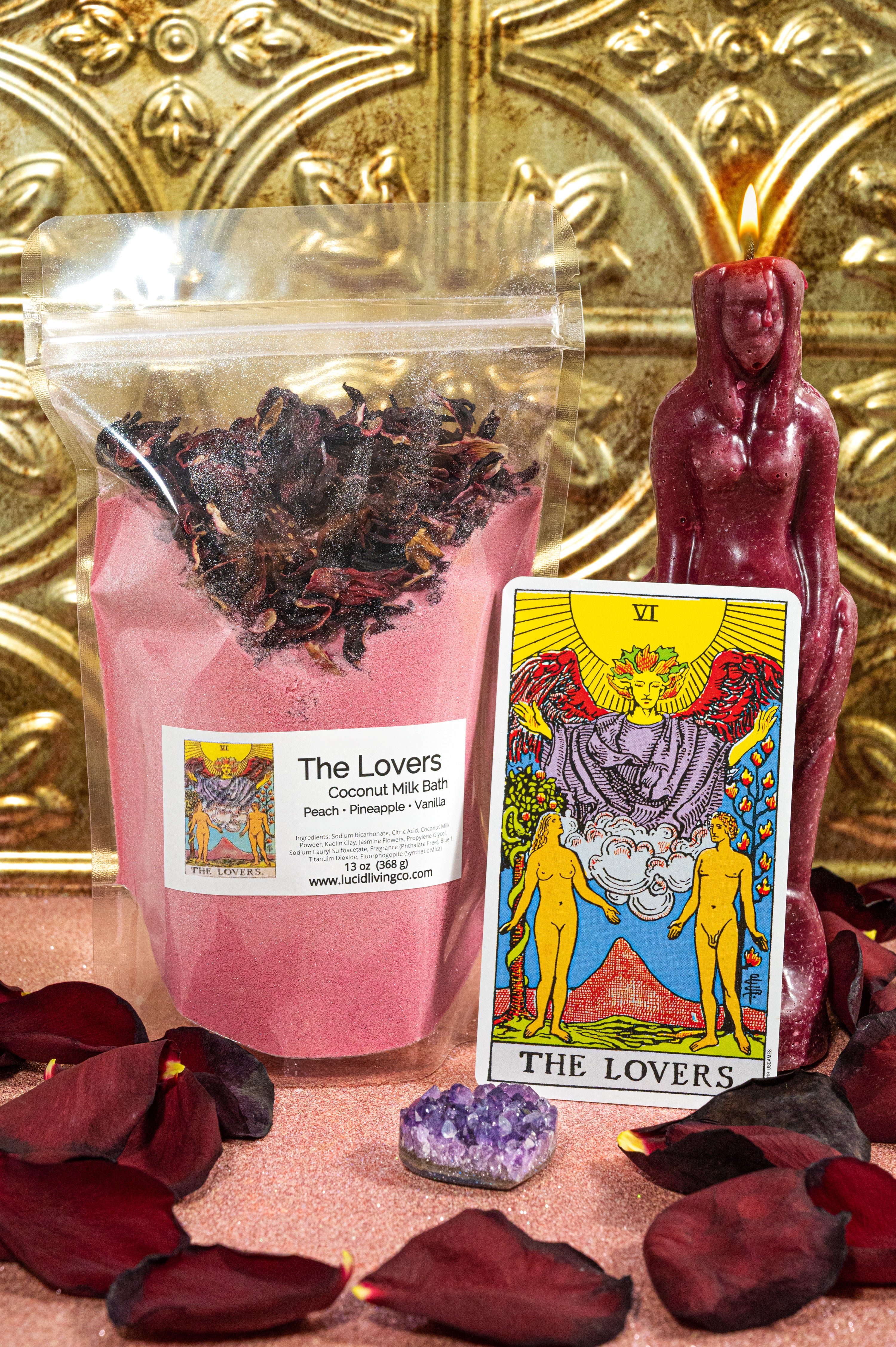 The Lovers Coconut Milk Bath powder with dried hibiscus, tarot card, candle, amethyst, and rose petals against gold backdrop.