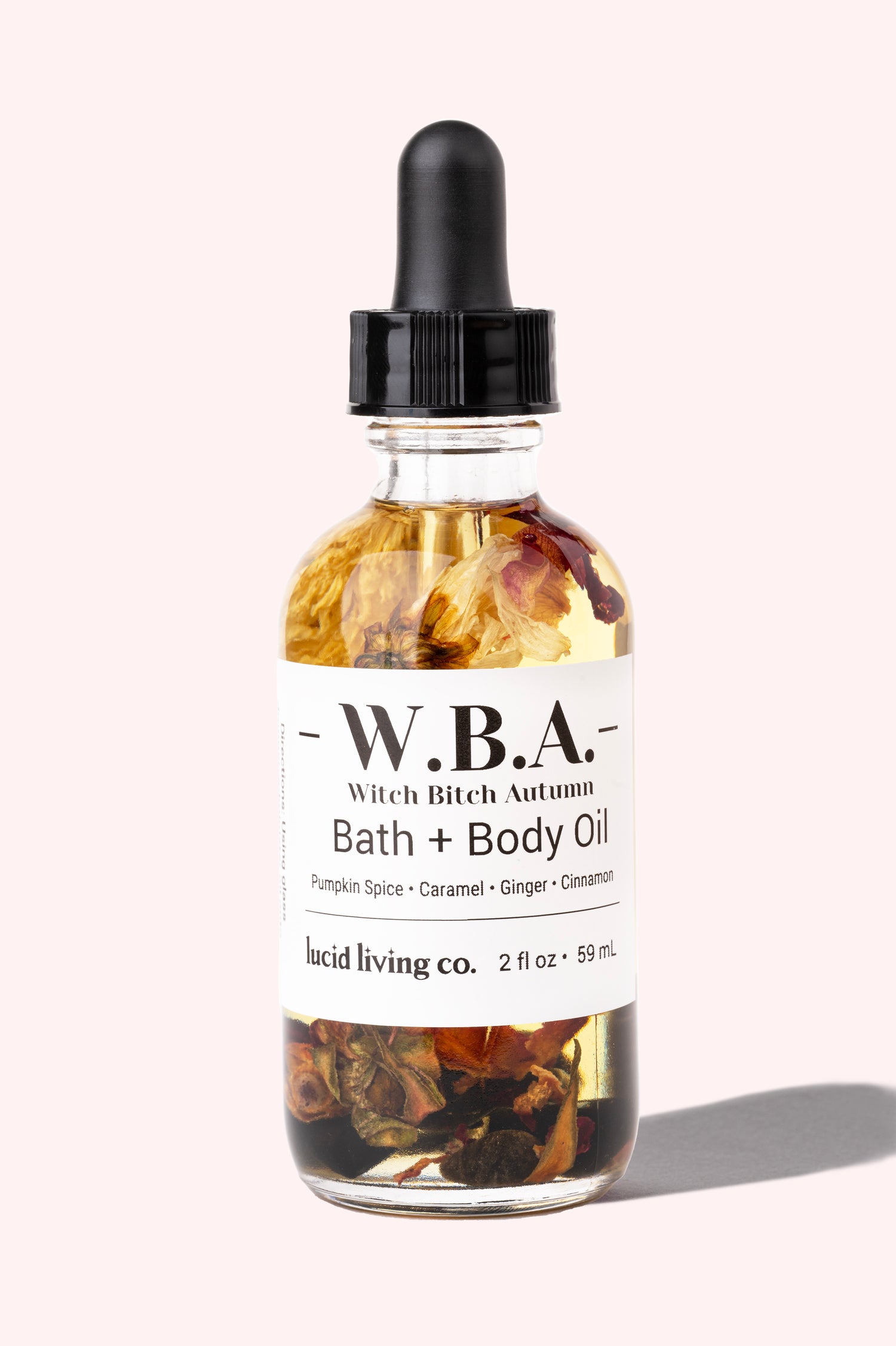 W.B.A. Witch Bitch Autumn Bath & Body Oil with pumpkin spice, caramel, ginger, cinnamon, and crystal chips in a clear bottle.
