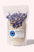 Clear pouch of MANIFEST Soothing Salt Soak with dried cornflowers and Palo Santo scent visible inside.