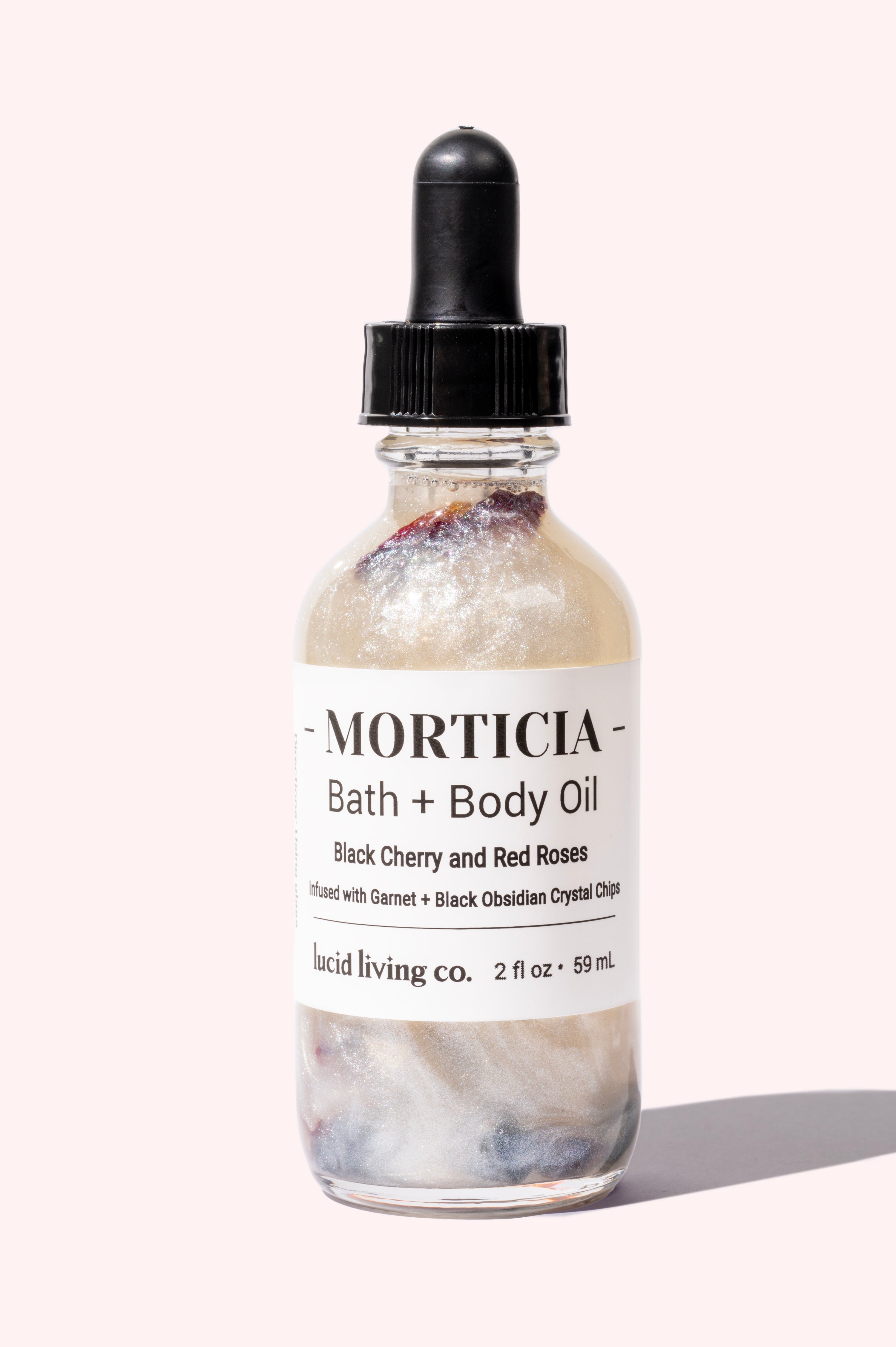 MORTICIA Bath & Body Oil with black cherry, red roses, garnet and black obsidian crystal chips in a clear dropper bottle.