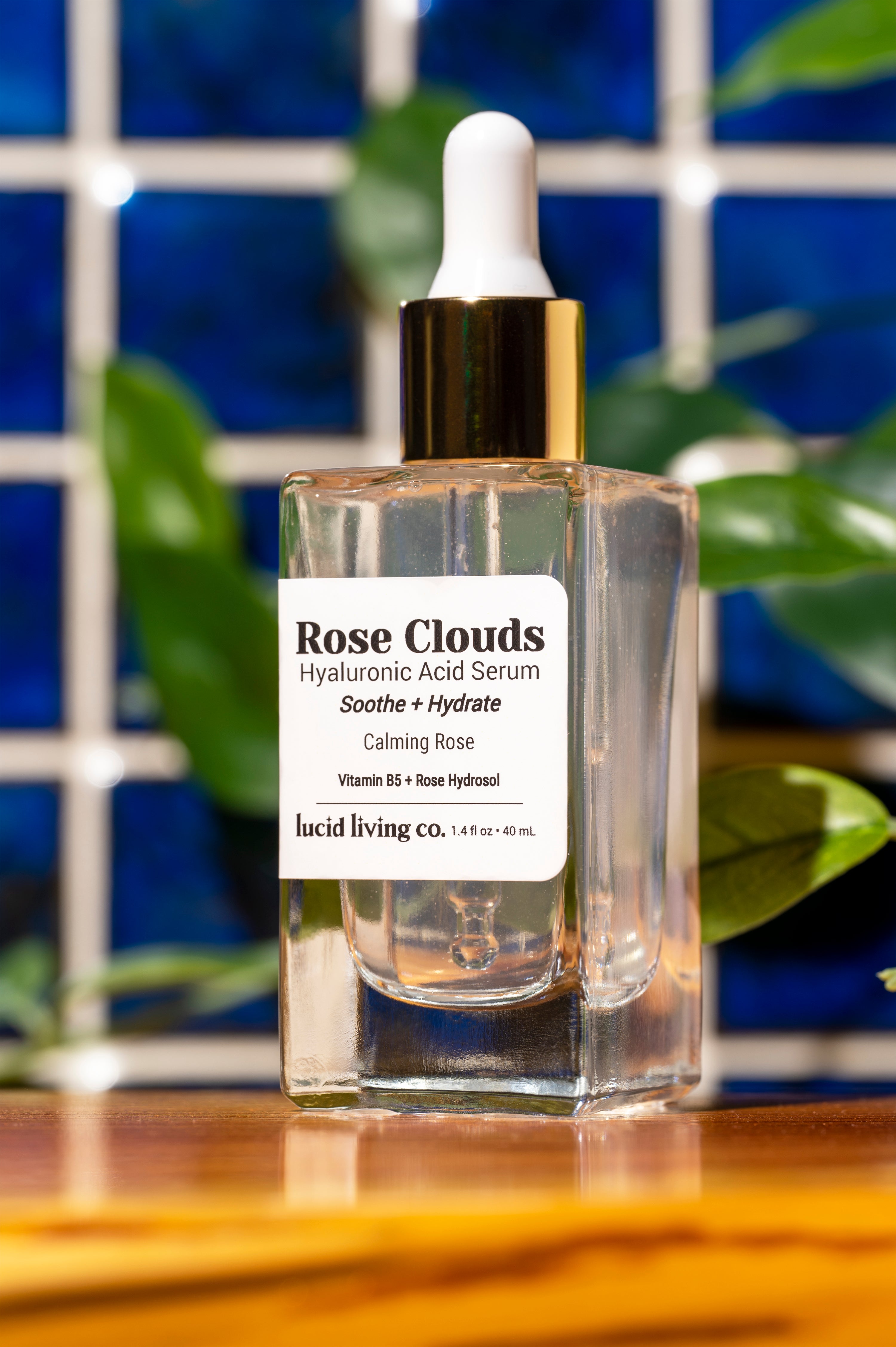 Rose Clouds Hyaluronic Acid Serum bottle with soothing rose hydrosol and Vitamin B5 on wooden surface.