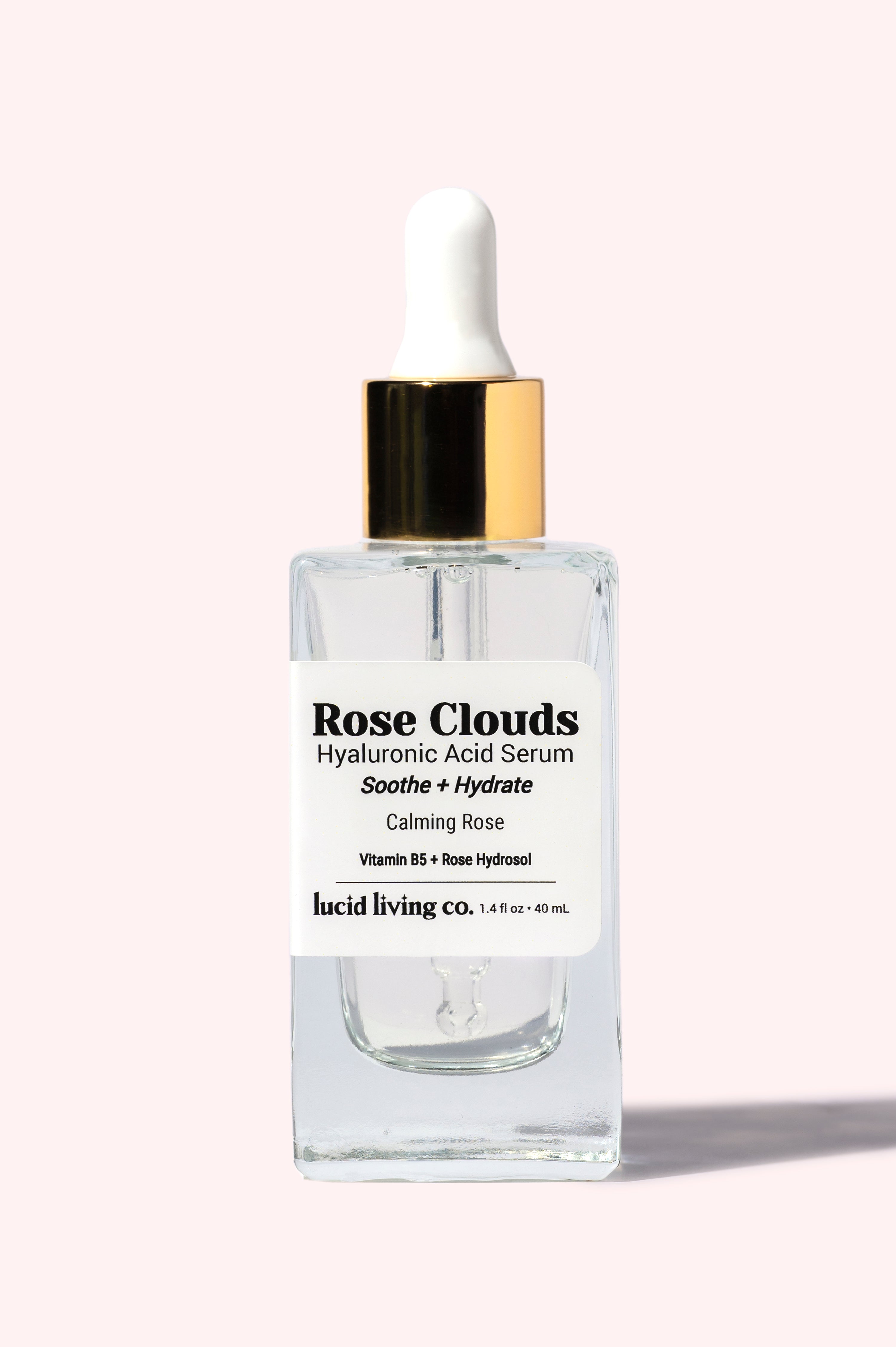 Rose Clouds Hyaluronic Acid Serum in clear glass bottle with dropper, hydrating and soothing with rose hydrosol and Vitamin B5.