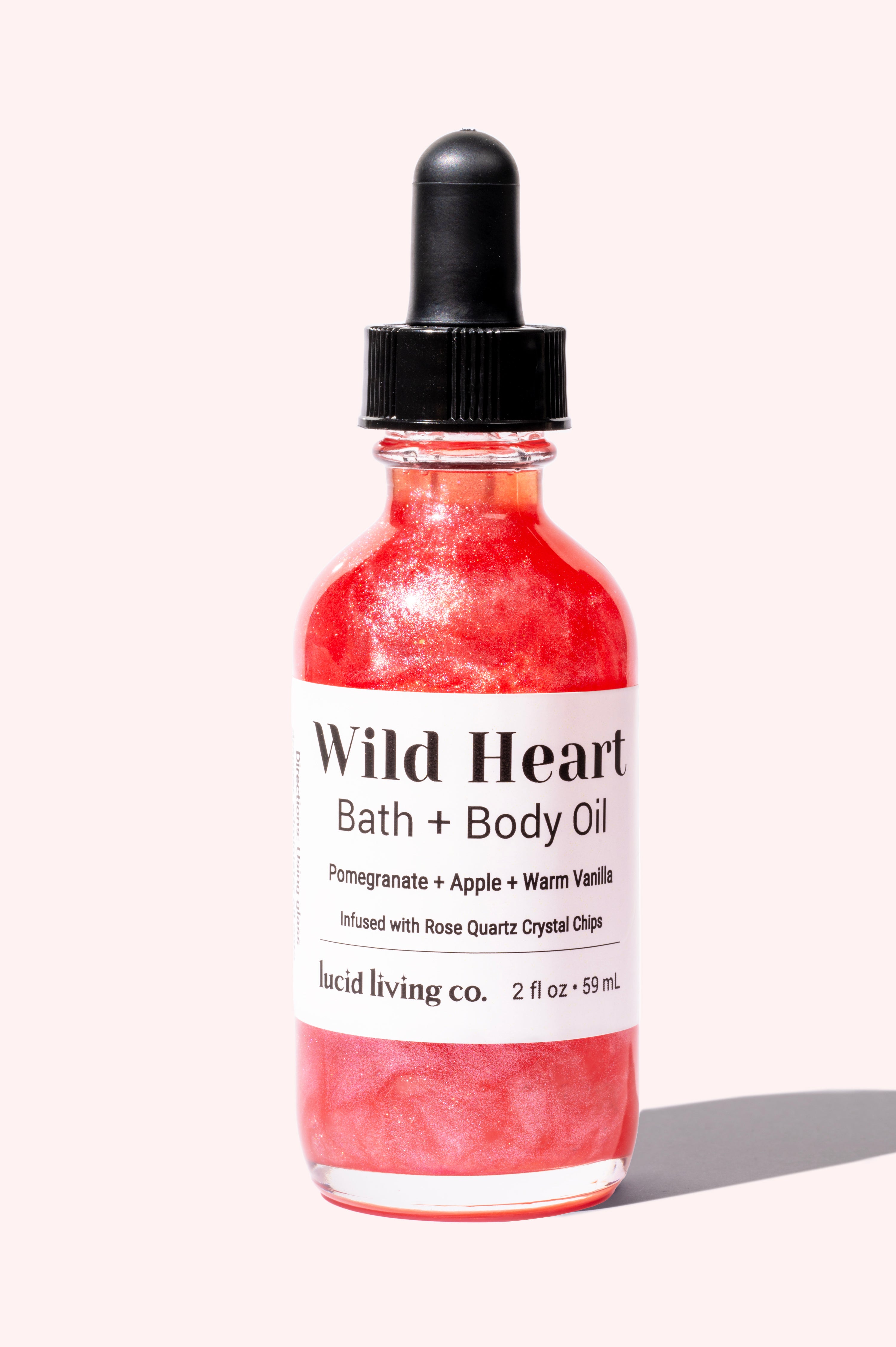 Wild Heart Bath & Body Oil shimmering pink bottle with pomegranate, apple, vanilla, and rose quartz crystal chips.