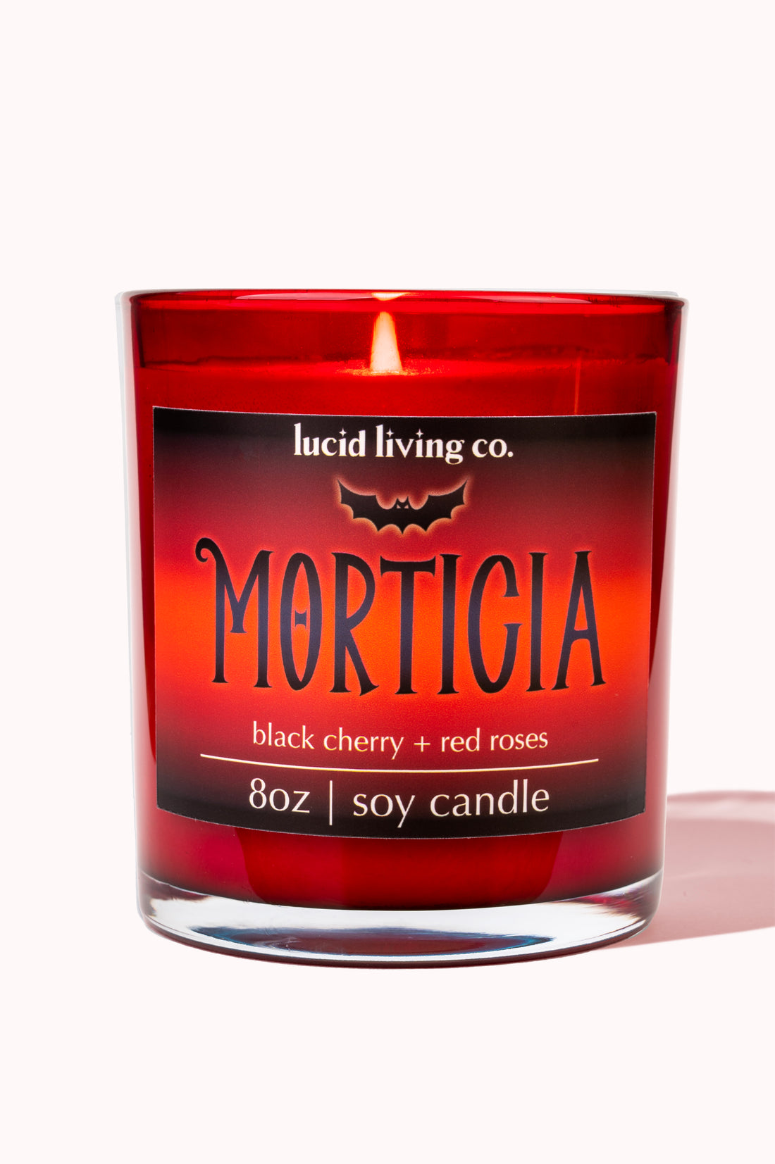 Morticia Soy Candle in red glass with black cherry and red roses scent burning inside an 8oz soy candle.
