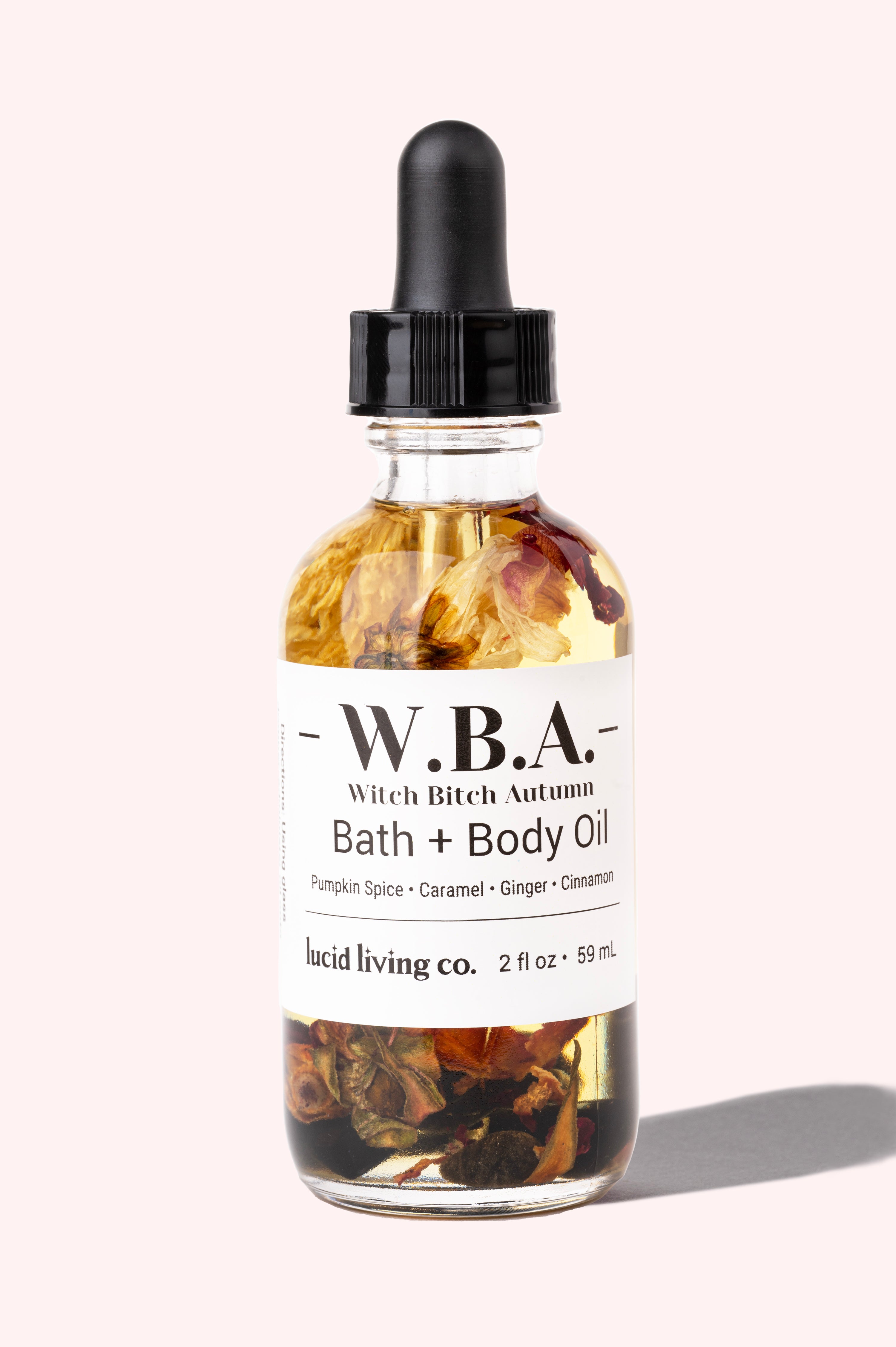 W.B.A. Witch Bitch Autumn Bath &amp; Body Oil with pumpkin spice, caramel, ginger, cinnamon, and crystal chips in a clear bottle.