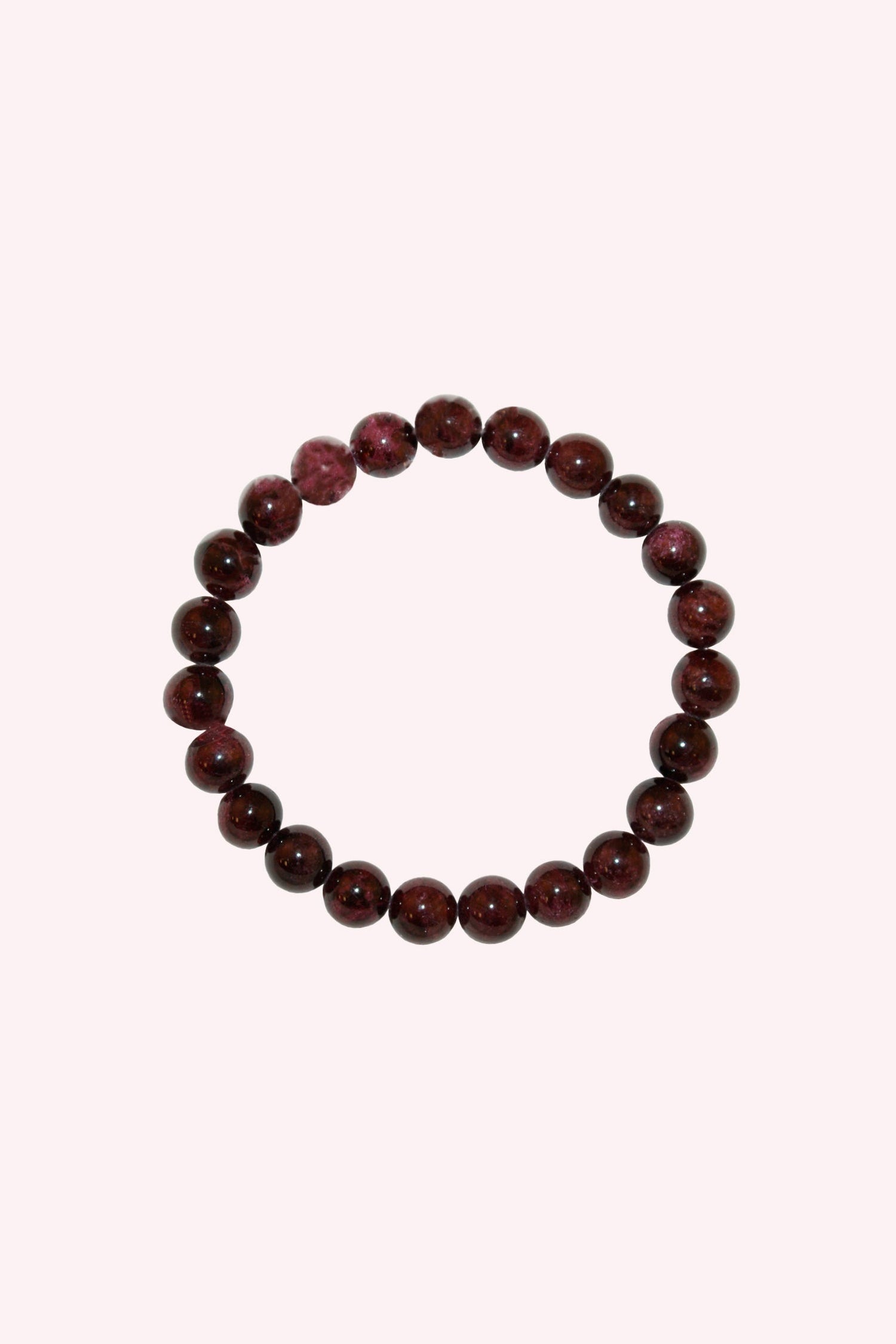 Garnet Crystal Bracelet featuring polished deep red beads arranged in a circular stretch design, highlighting the natural beauty and rich tones of garnet gemstones against a soft pale background.