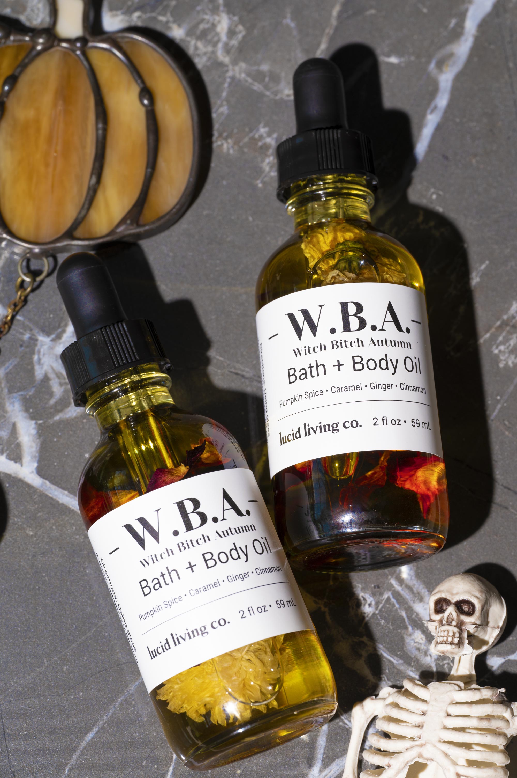 Two bottles of W.B.A. Witch Bitch Autumn Bath &amp; Body Oil with pumpkin spice and Goldsheen Obsidian crystals.